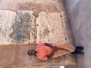 a woman posing in front of a wall in the Colosseum