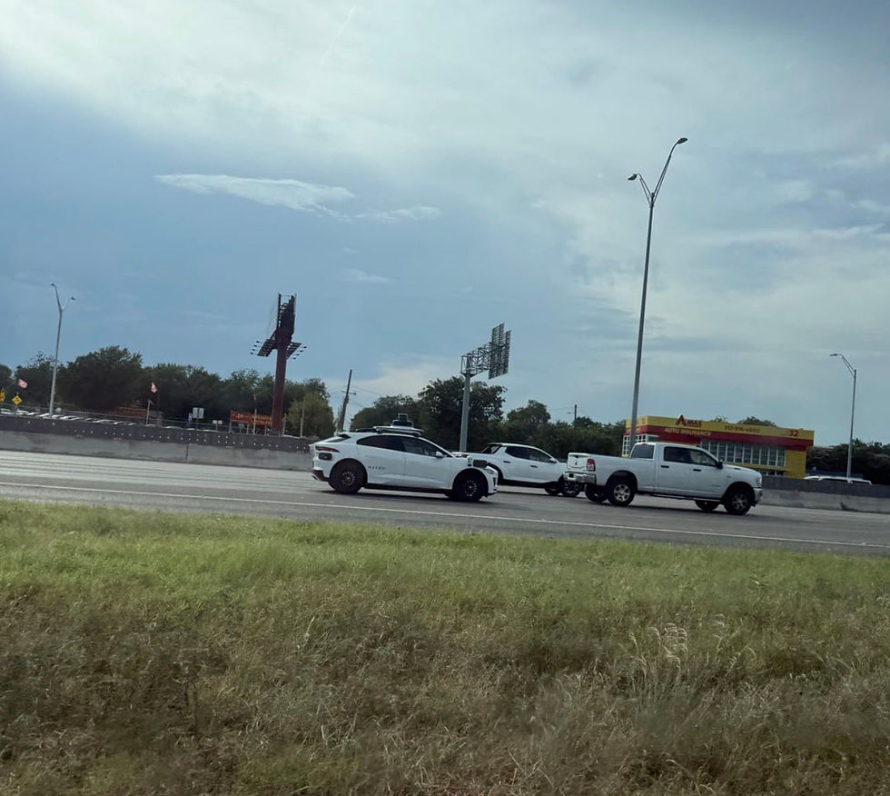 White cars on a highway in daylight, with a Max Auto Repair shop in the background. Sky is overcast, and the mood is calm. Waymo in the background in Austin, Texas