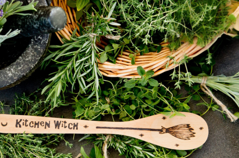 Basket of herbs on a kitchen counter with a wooden spoon and pestle and mortar.