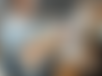 Artist drawing at an easel with a curious orange cat on her lap in a warm, creative studio space.