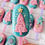 Thumbnail: Close-up of a teal Christmas cakesicle decorated with a pink chocolate Christmas tree, gold star and white star sprinkles.