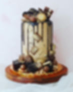 Luxury tall chocolate drip cake decorated with gold accents, chocolate bars, brownies, and chocolate-covered treats.