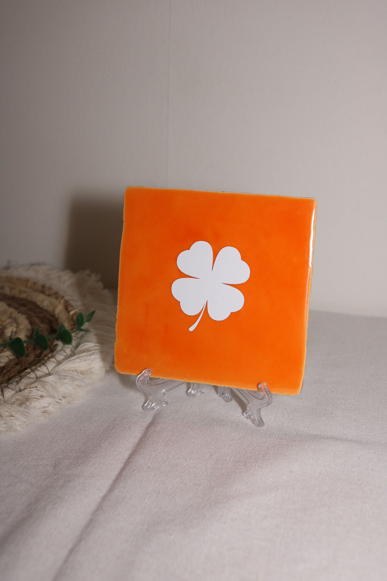 Oranje tegel met wit klavertje vier