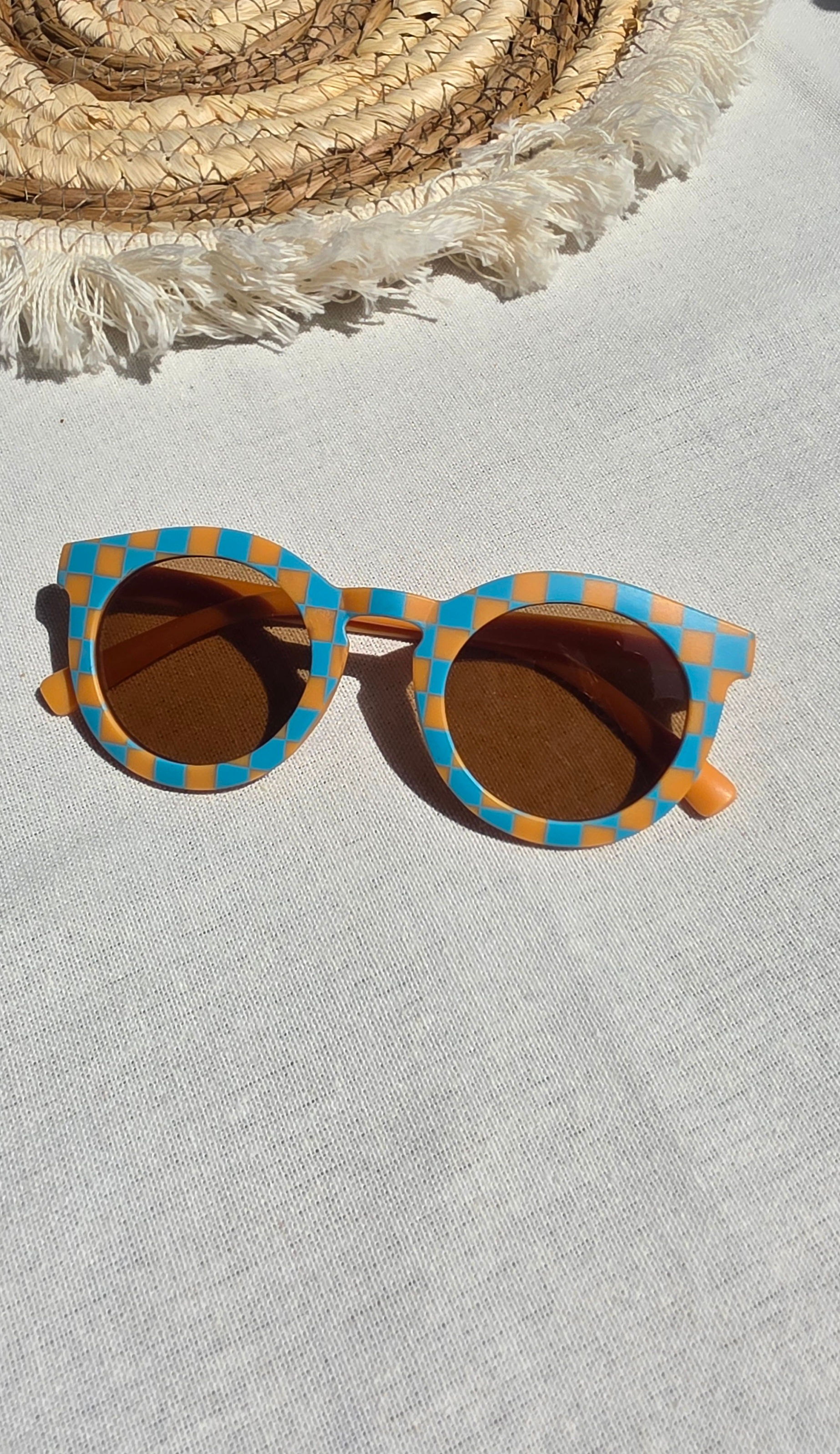Ronde retro kinderzonnebril met oranje en blauw geruit dambordpatroon