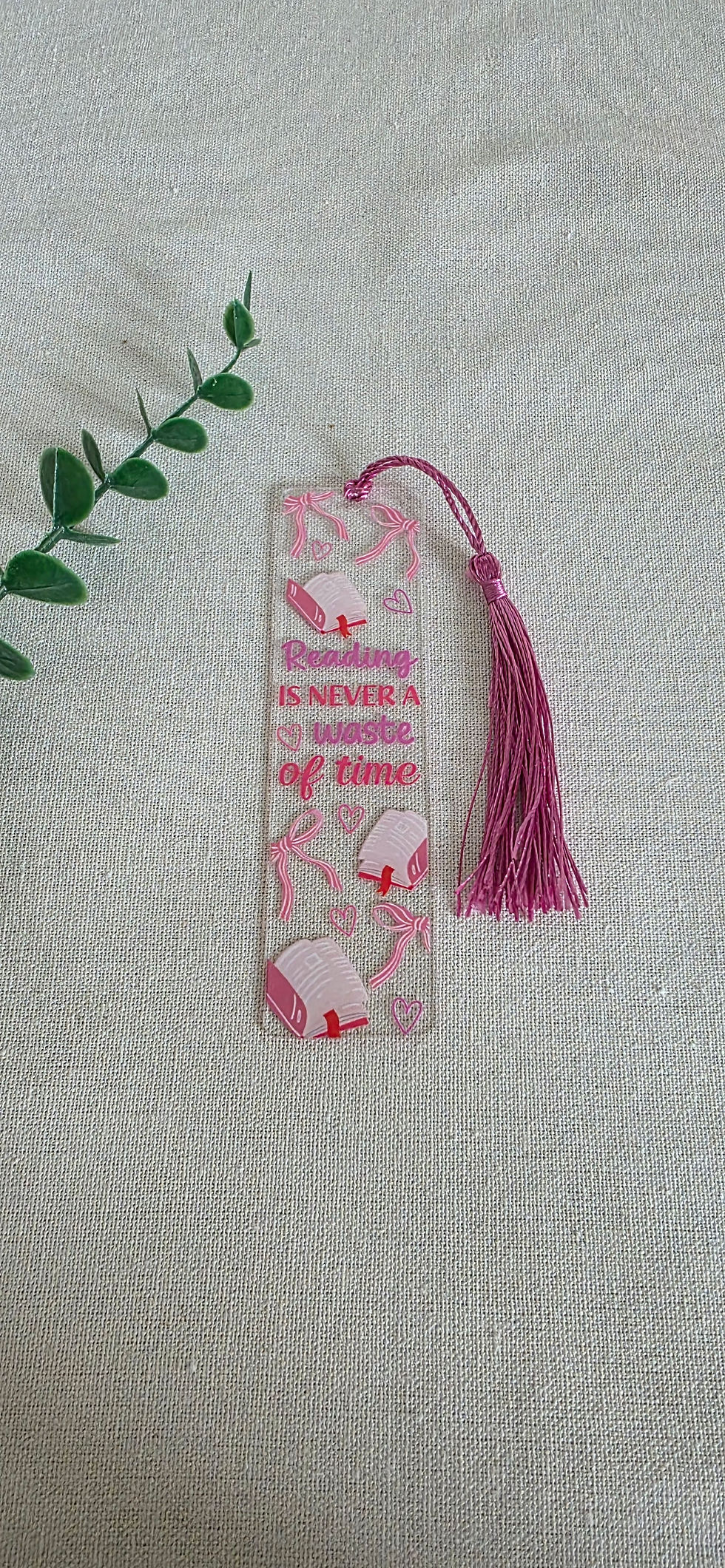 Transparante acryl boekenlegger met de tekst reading is never a waste of time, versierd met roze strikjes en hartjes