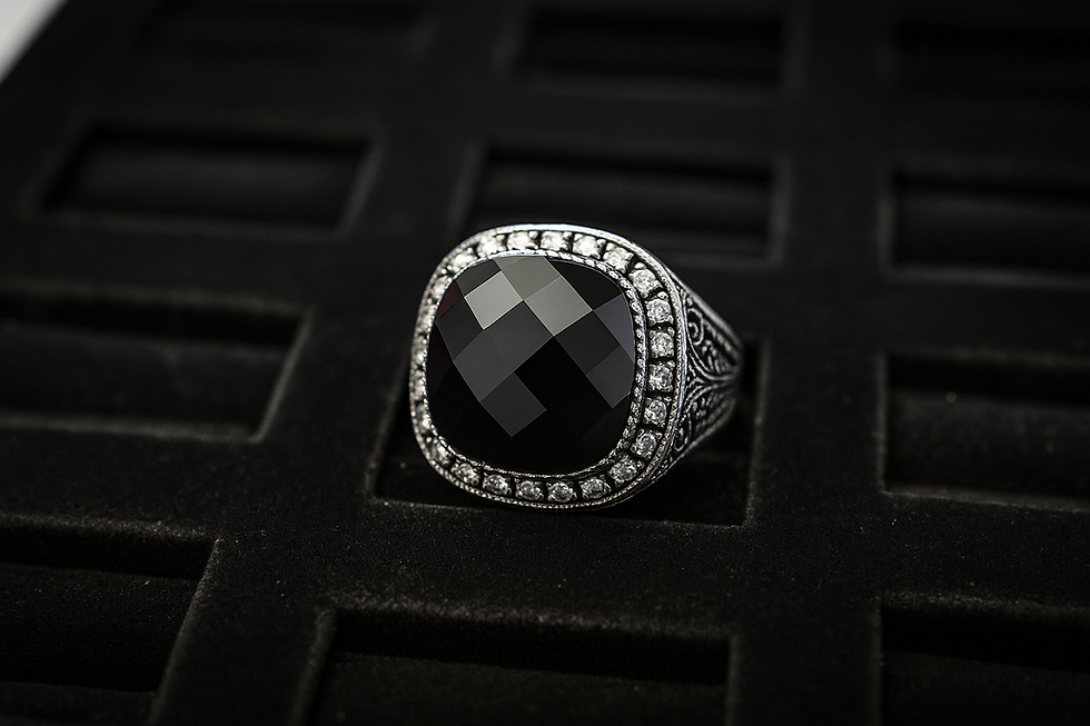 Close-up of a black gemstone ring with diamond accents on a black surface.