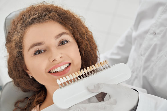 woman-smiling-while-male-dentist-keeping-teeth-color-range.jpg