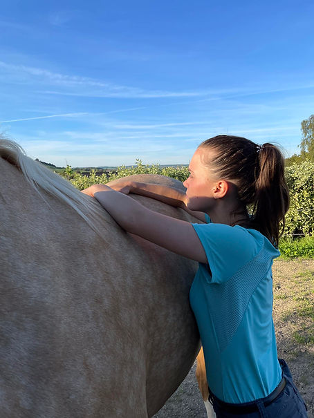 Elodie, l'ostéopathe, les mains posées sur le dos d'un cheval, prête à le manipuler.