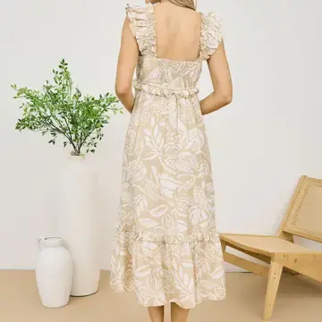 A beige midi dress with a white tropical print, featuring a square neckline, ruffled shoulder straps, and an elasticized waist with a tiered ruffle hem.