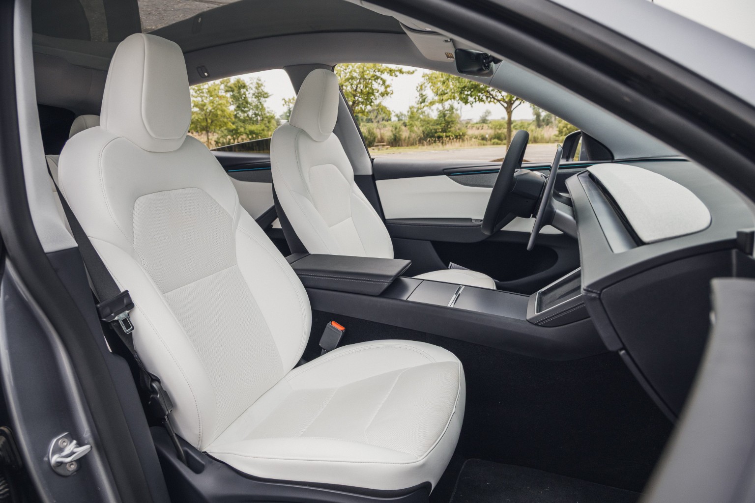 Tesla-style interior photograph: White-seat cabin · Side view