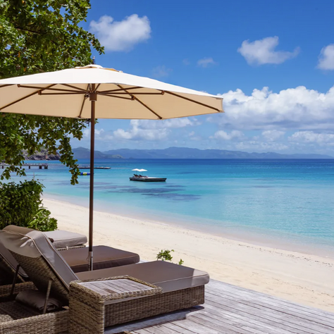 Sun beds & umbrella on a white sandy beach with bright blue sea 