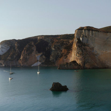 Mediterranean coastline overlooking yachts moored on a calm sea.
