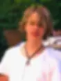 Close-up portrait of Francesco, with wavy blond hair and a white T-shirt, standing outdoors.