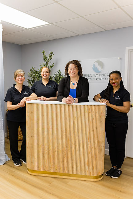 The Perfectly Kneaded massage therapy team smiling behind the front desk.
