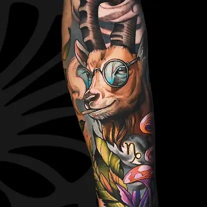 קעקוע נאו-טרדישיונל צבעוני של עז היפית עם משקפיים על הזרוע בתל אביב.