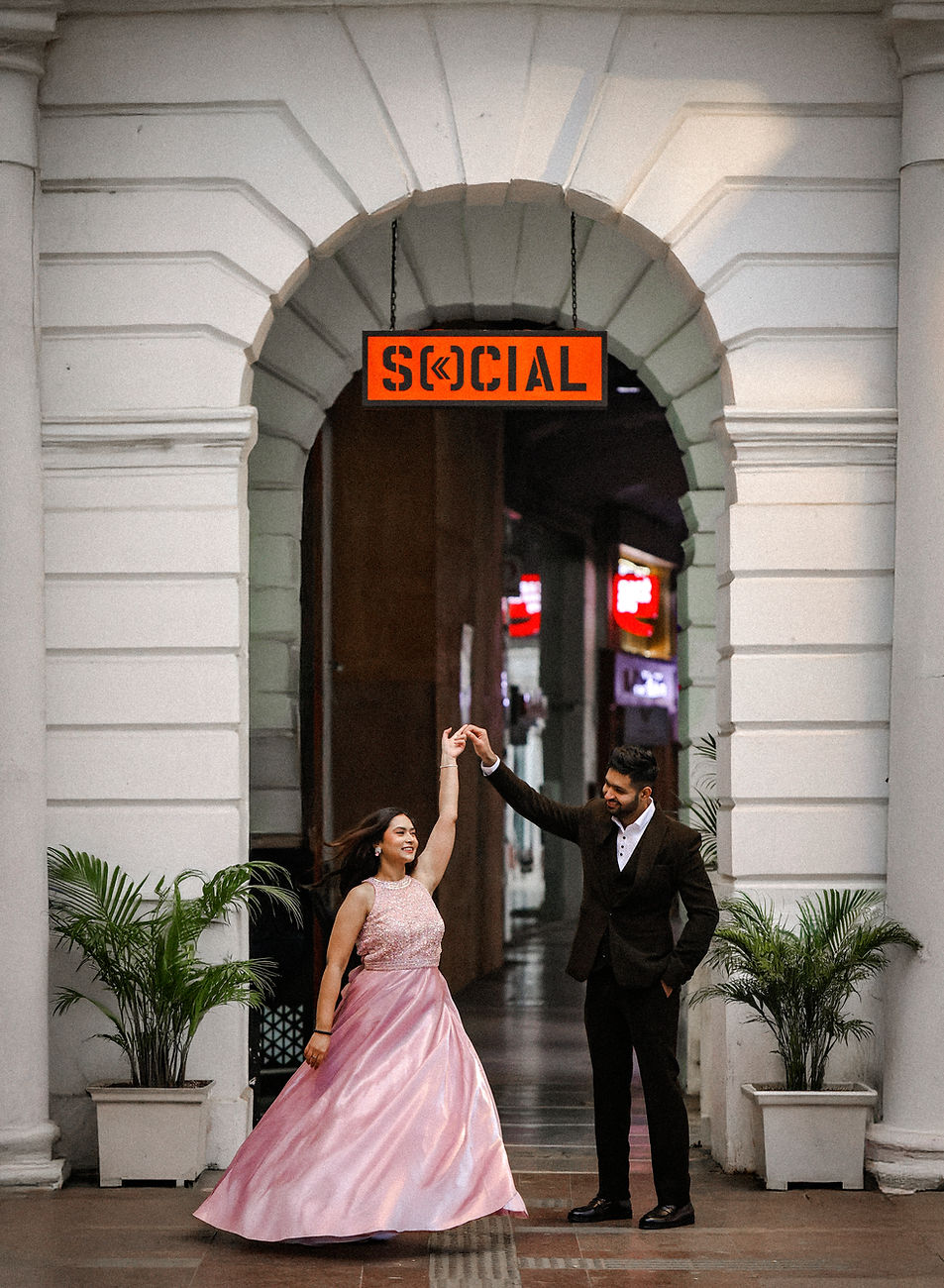 Romantic pre-wedding portrait of couple walking through the iconic white colonnades of Connaught Place, Delhi