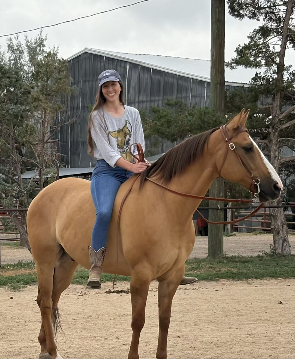 Smiling woman riding a light brown horse.