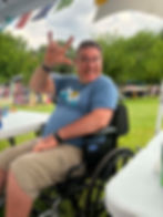 Man in a wheelchair making the 'I love you' sign.