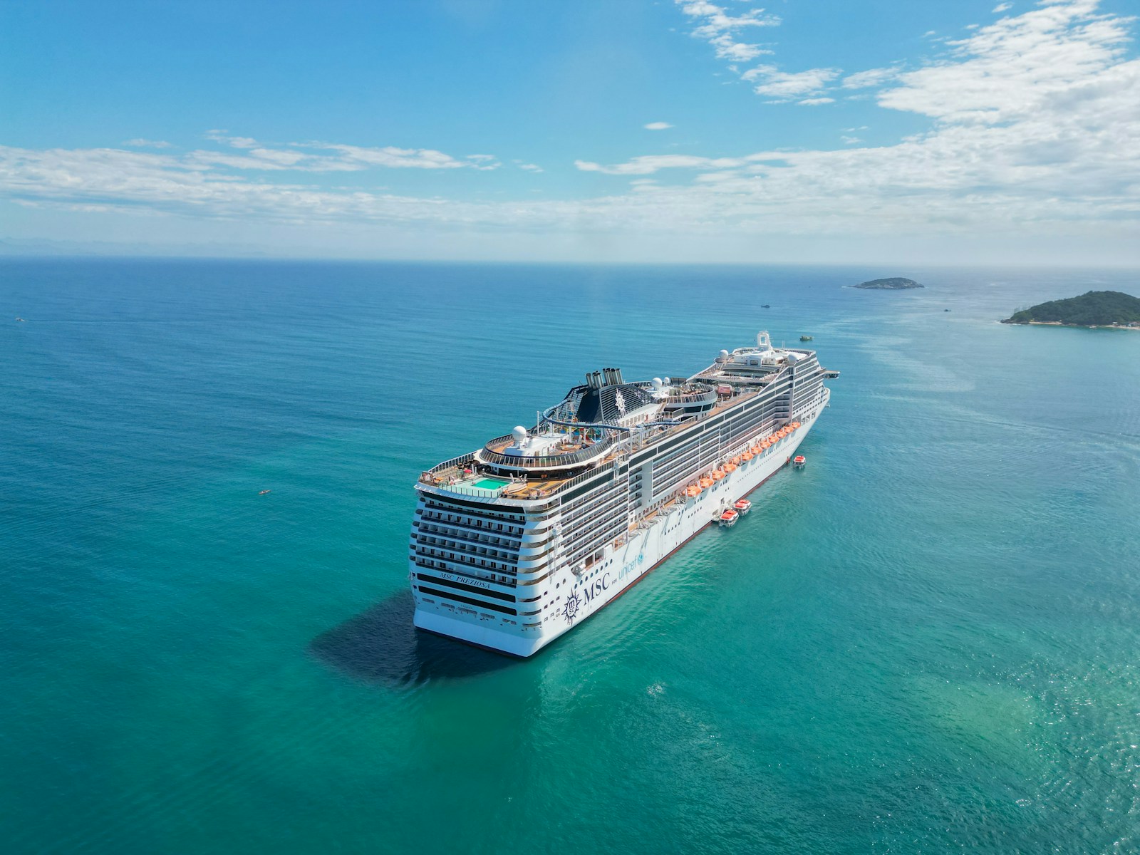 A white cruise ship surrounded by turquoise water, photographed by Charles Assunção
