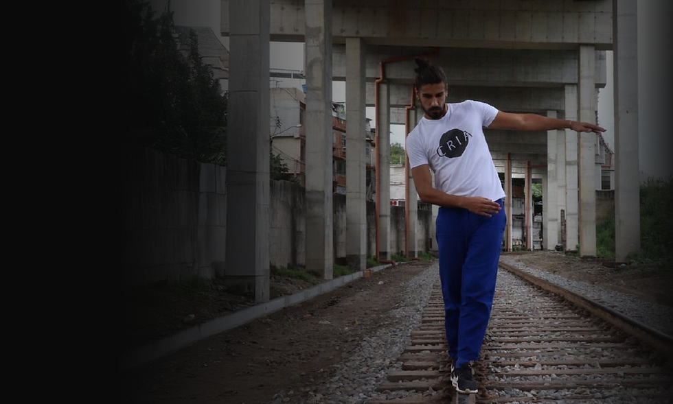 Jovem embaixo de um viaduto posando com a camisa do projeto cria