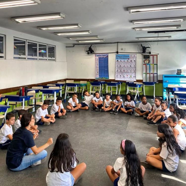 Professor do Projeto Cria dando aula para alunos de um colégio público. Os alunos estão sentados em círculo.