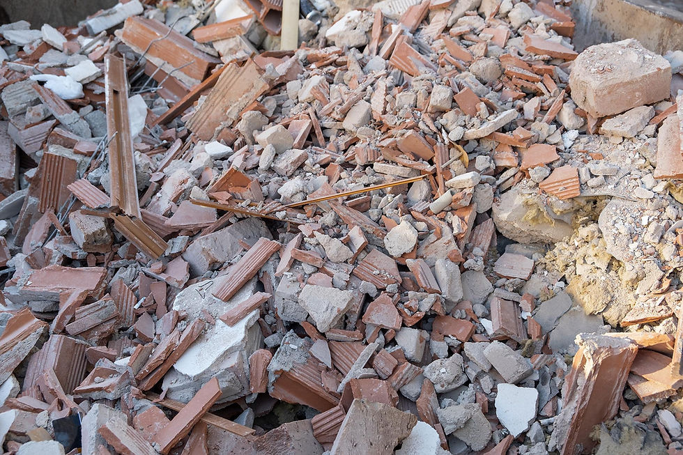 Pile of rubble with broken bricks and concrete, mostly reddish-brown and gray. No visible text. The scene appears chaotic and desolate.
