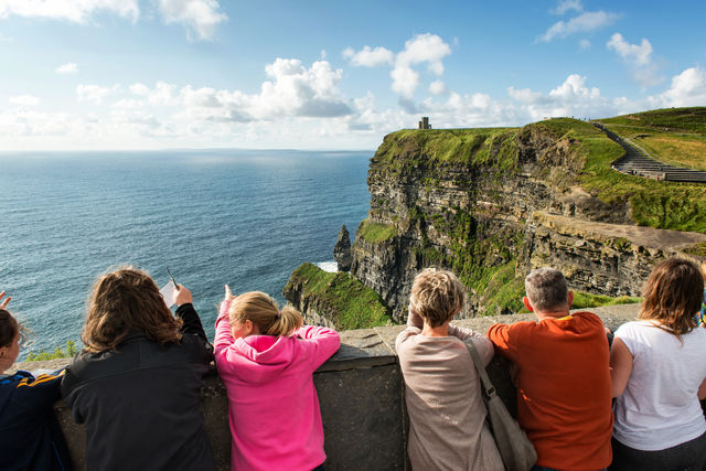 Tourists overlooking the Cliffs of Moher, ocean and sky view; Essential Ireland Tours