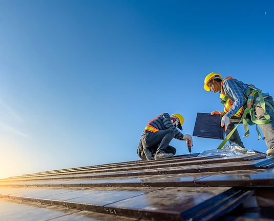 Roofers in safety gear installing shingles on a house.