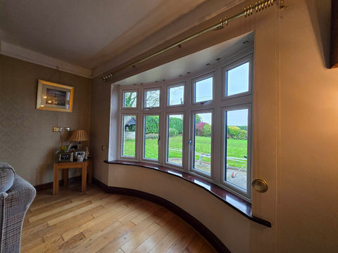 Interior view of a curved bay window overlooking a green lawn. UPVC Windows.