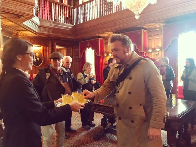 Man in beige coat receives a brochure inside building; Essential Ireland Tours