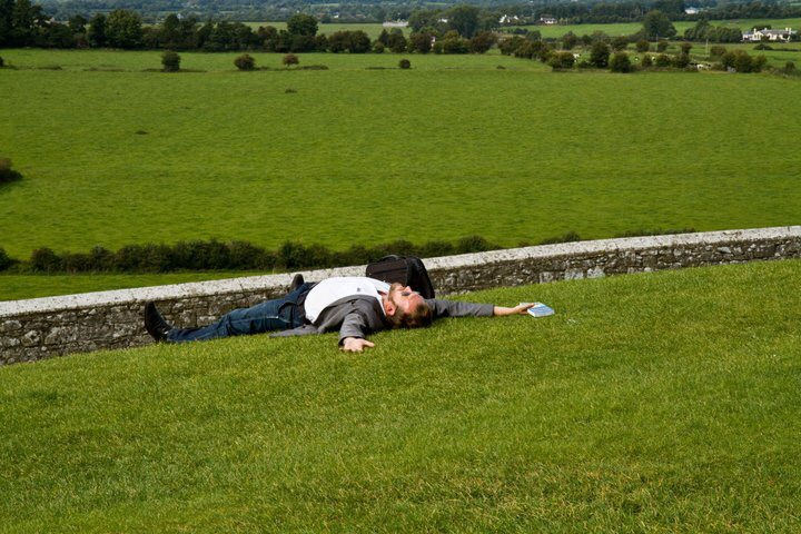 Man lying on grass. Green fields in background. Essential Ireland Tours
