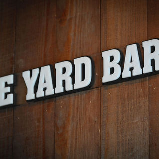 White text spelling THE YARD BAR on brown wooden wall Carpenter'sBarLounge