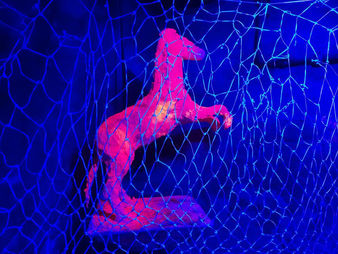 Pferdeskulptur aus Gips  im Schwarzlicht leuchtet orange