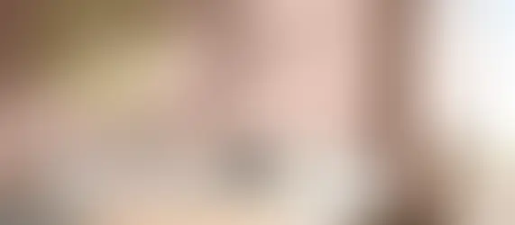 Interieurfoto met zachtroze wanden, lichte designbank en kleurrijke accenten.