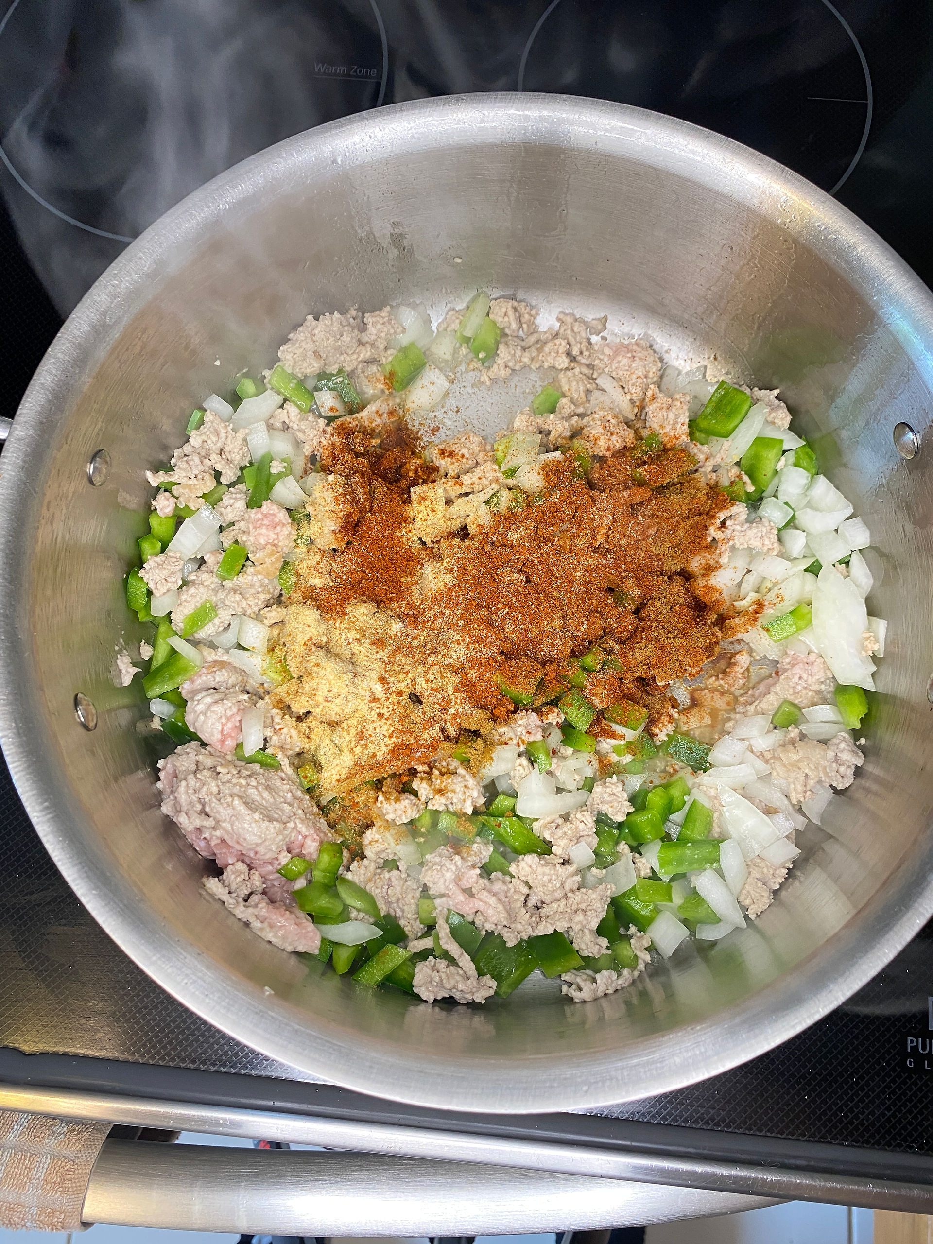ground turkey, peppers and onions and spices in a large silver pot being sauteed for pumpkin chili