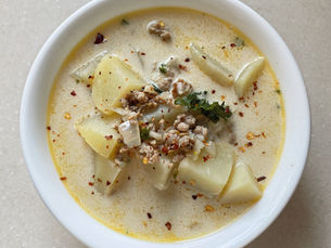 looking down into a while bowl filled with creamy white zuppa toscana soup with pops of green kale and crushed red pepper flakes on top as a garnish