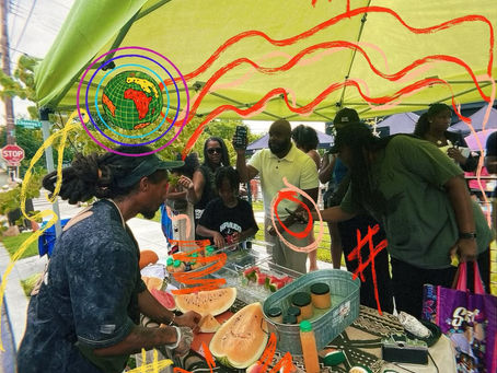 close-up of a melon nation co-founder slicing seeded watermelon beneath a bright yellow-green market tent, surrounded by hand-drawn neon illustrations in red, orange, & green; watermelon halves rest across the table while a co-founder prepares fresh fruit outdoors on a sunny day.