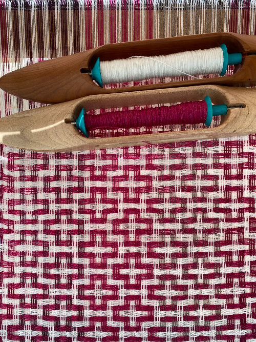 Thumbnail: pink and white handwoven mosaic patterned merino scarf being woven on the floor loom