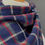 Thumbnail: patterned tartan plaid navy wool shawl draped around a mannequins shoulders against a dark grey wall