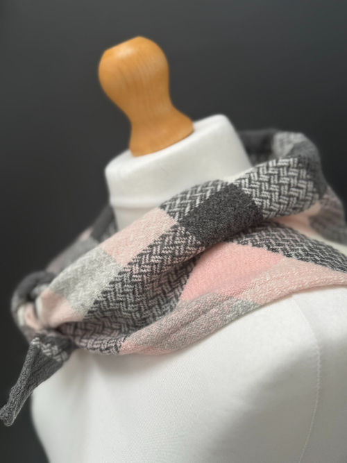 grey white and pastel pink merino wool triangle scarf on a mannequin against a dark grey background