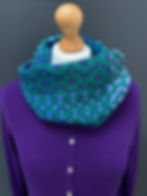 Handwoven peacock merino snood styled with a purple cardigan — showing colour coordination, made by Emma Baker