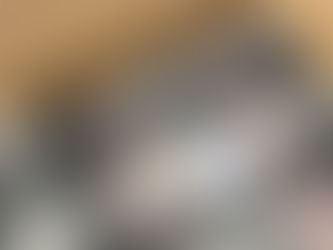 Plaid gray and pink textile with a tag lies on a wooden surface. A cardboard box labeled "Emma Baker Handwoven Textiles" is beside it.