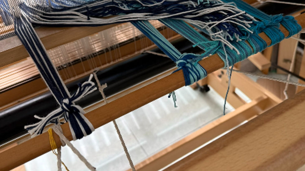 Wooden loom with blue and white threads being woven. The setting appears bright and detailed with no visible text.