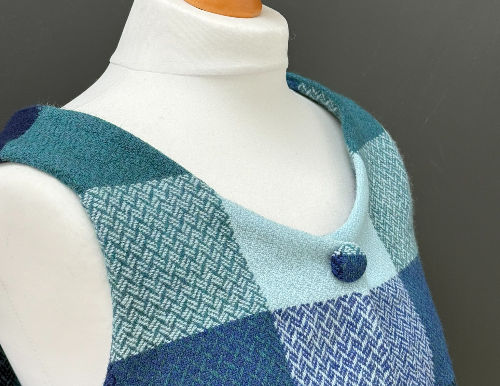 Close-up of a mannequin wearing a blue and teal patterned sleeveless dress against a gray background