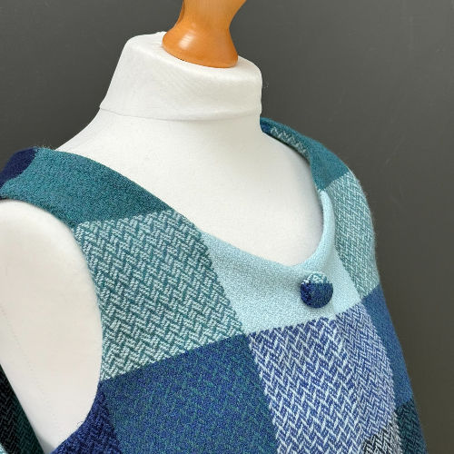Close-up of a mannequin wearing a blue and teal patterned sleeveless dress against a gray background