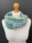 pale mint green and white intricately patterned snood scarf on a mannequin against a dark grey wall