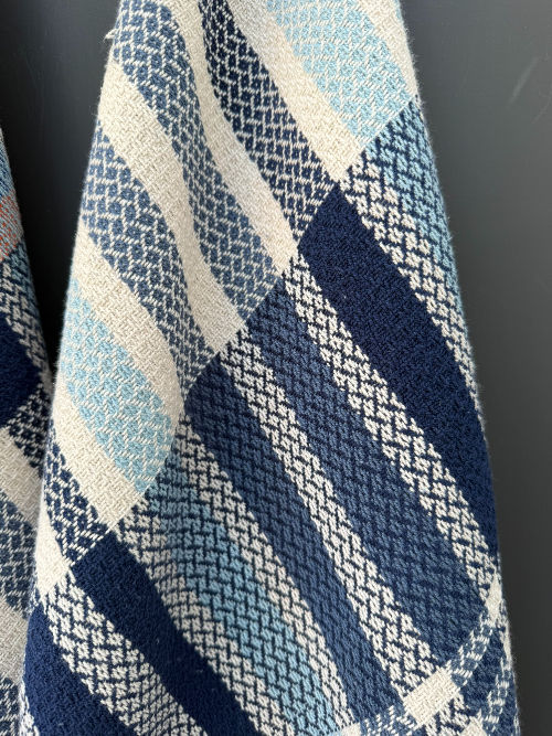 Thumbnail: navy blue and white tea towels hung up against a dark grey back ground