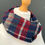 Thumbnail: red navy patterned wool snood scarf on a mannequin against a dark grey background