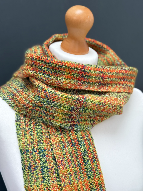 side ways view of a green and orange handwoven scarf on a model