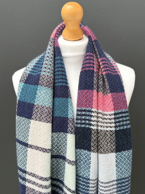 handwoven randomly patterned blue and pink scarf on a mannequin against a dark grey wall